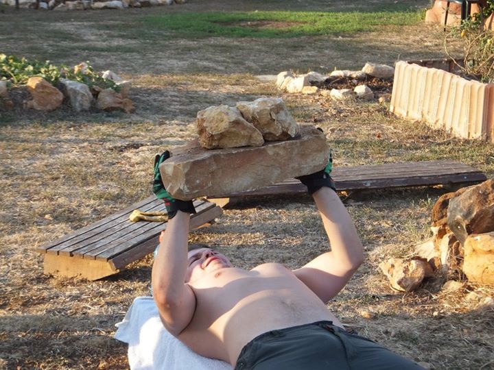 A man pushing rocks upward in an open rural space