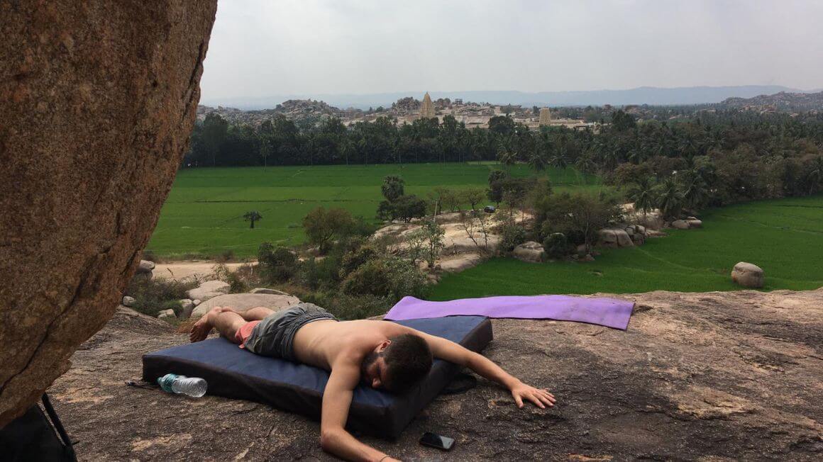 lying down on a mat after a session of bouldering in hampi, india