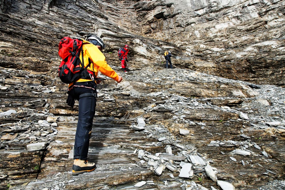 trekking up a rock wall with a harness