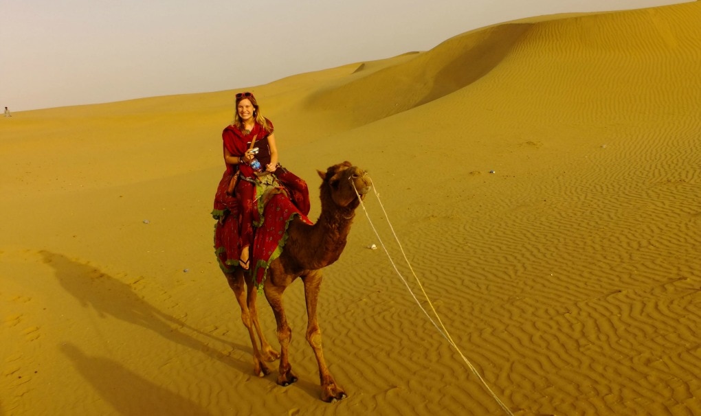 Backpacker on camel in Rajasthani desert India