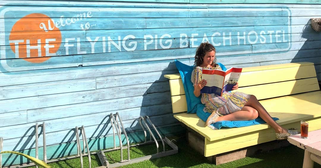 girl reading a book on a yellow bench at a hostel