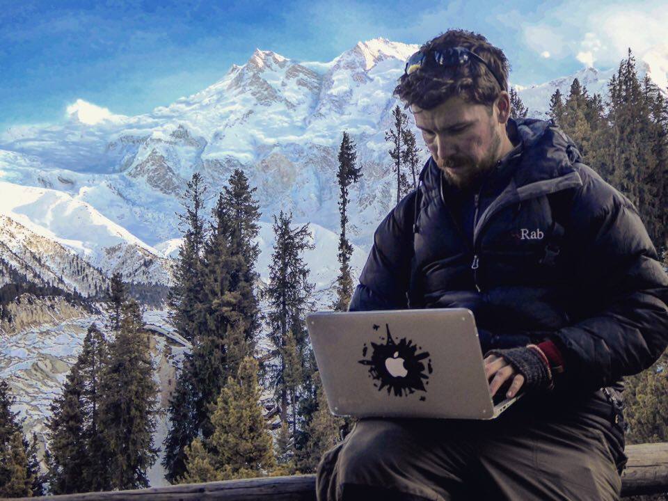 a man sitting at his laptop while backpacking in pakistan with insurance