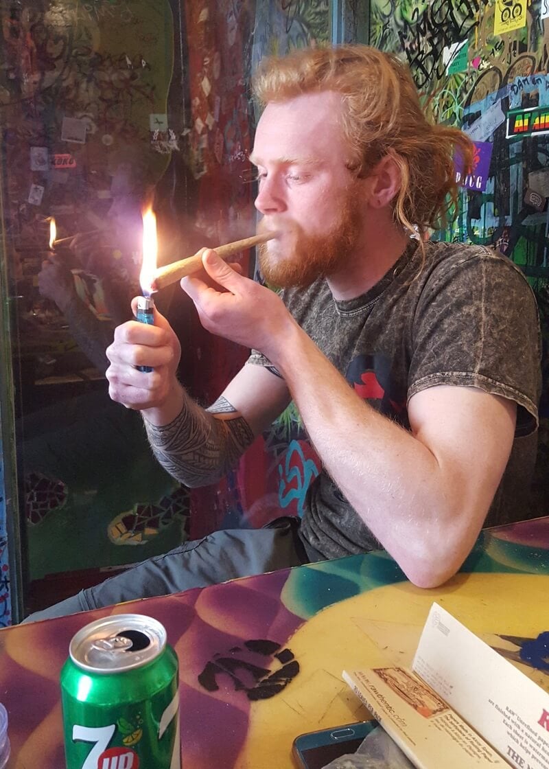 Ginger man lighting an oversized joint in a coffeeshop in Amsterdam