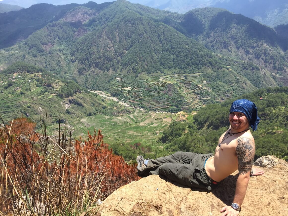 Will sitting on a rock topless in front of mountains