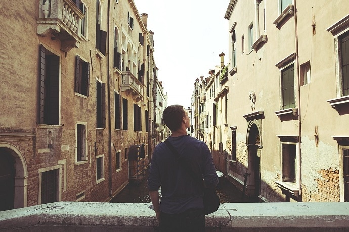 A dude looking at a street of potential investment opportunites so he can make money wile travelling