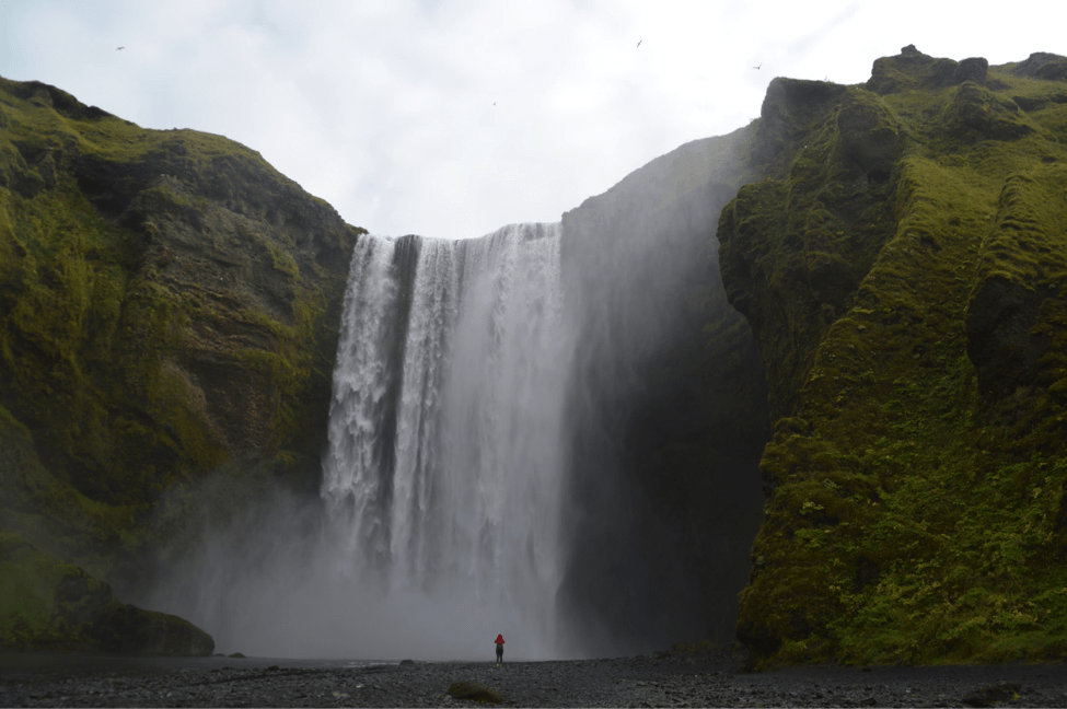 A person is made to look tiny next to a massive waterfall in Iceland