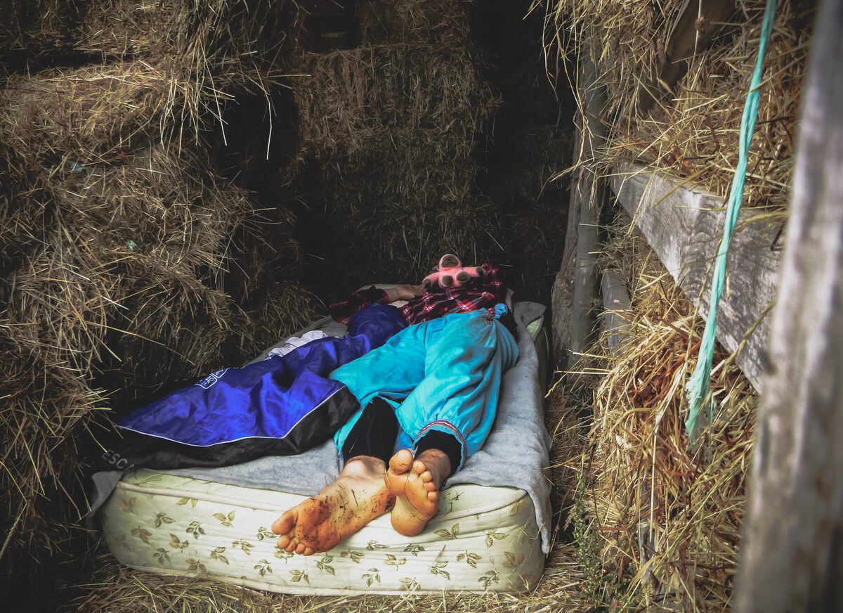 man lays on a mattress in a makeshift sleeping space