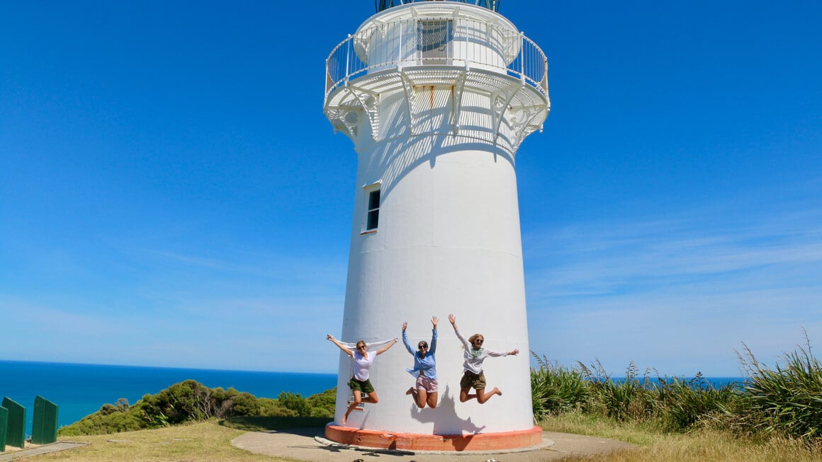 dani and friends jumping  in front of the east cape lighthouse, new zealand