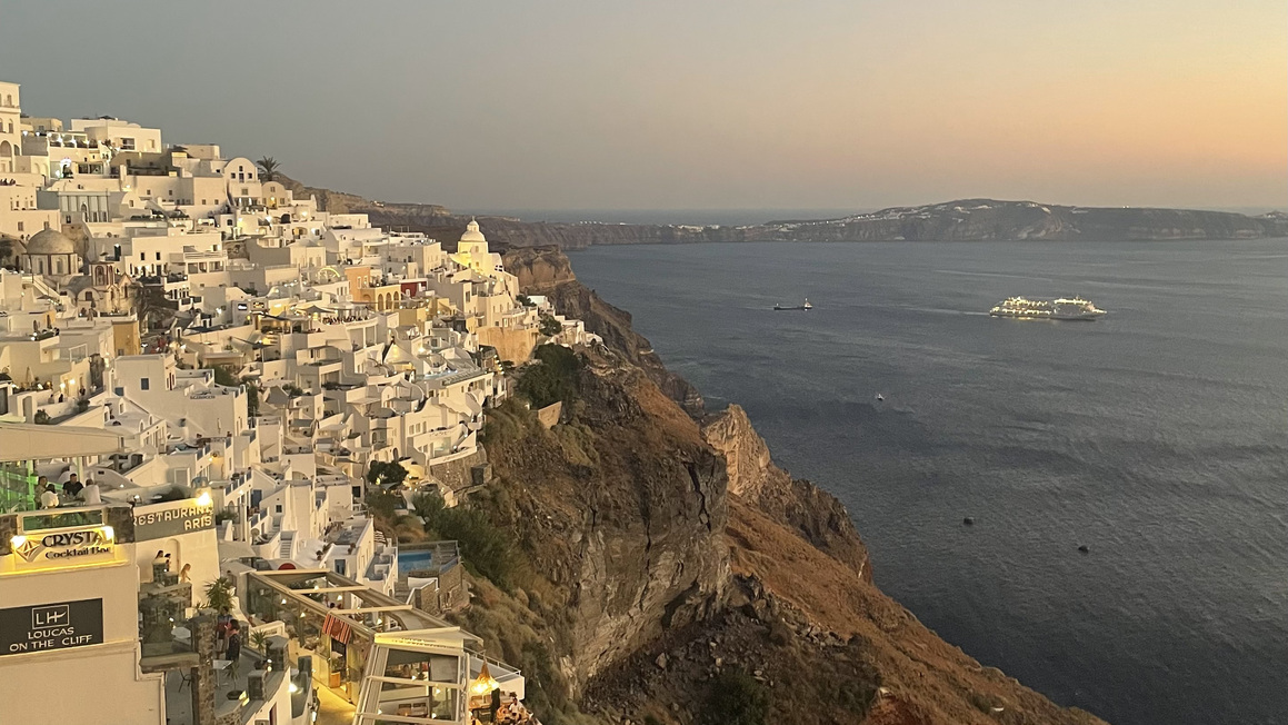 suset over the white buildings and sea in thira, sanotrini, greece