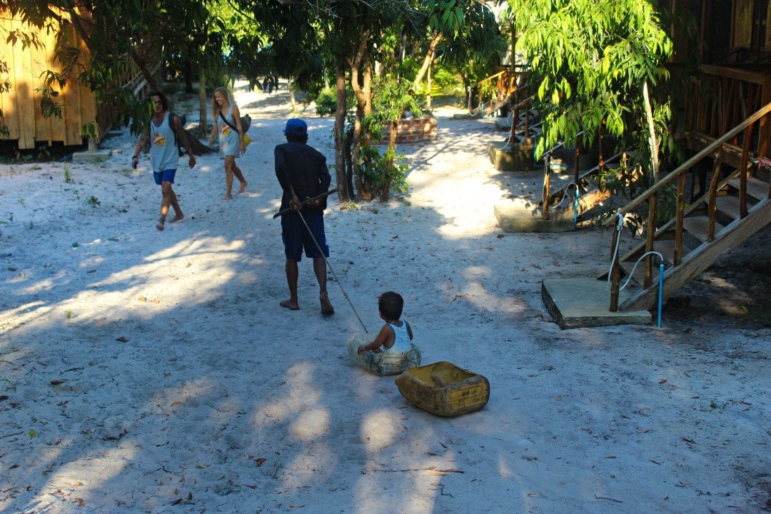 A Khmer man pulling his child in a sand sled in a tourist destination in Cambodia