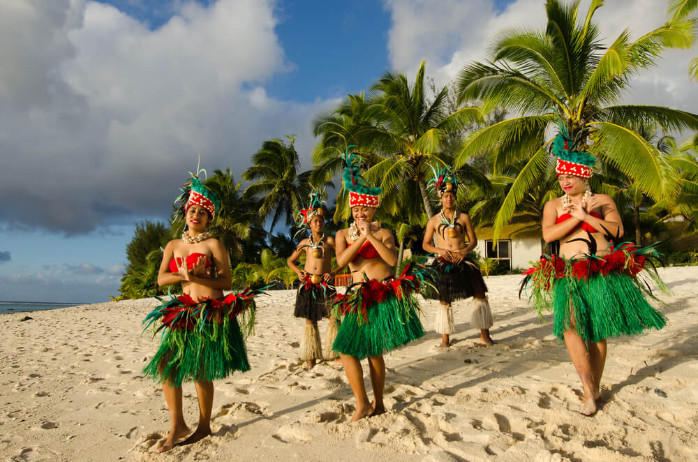 Welcoming party of local dancers on a beach in party to newly acccepted international tourists