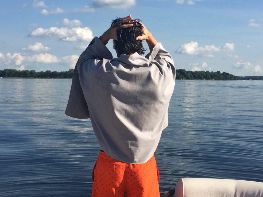 A man on an RV trip drying himself at a lake with his microfibre towel