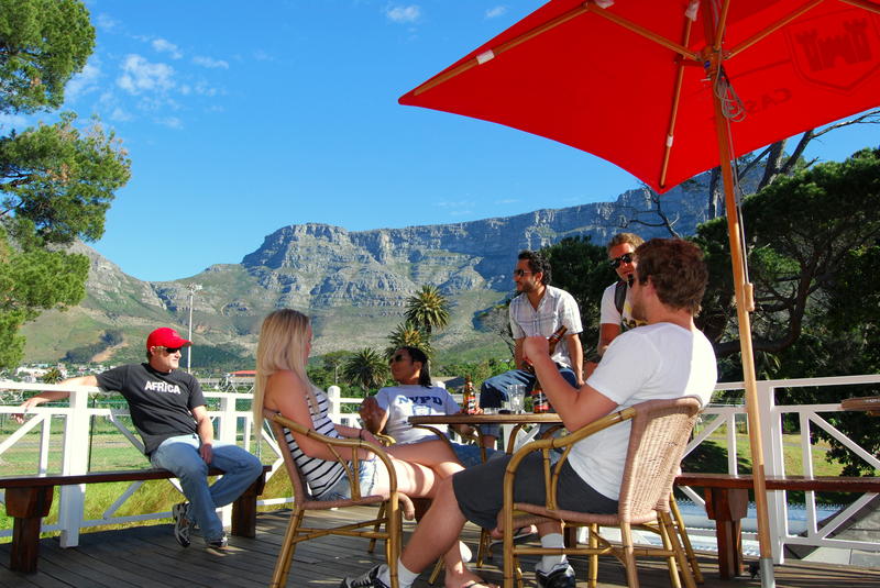 Ashanti Lodge Gardens Best Hostels in Cape Town. Outdoor table with people sitting around enjoying the view of Table Mountain.