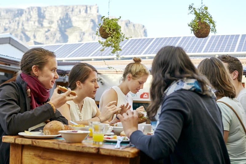 The Backpack Best Hostels in Cape Town. A group of friends sitting at the on site restaurant.