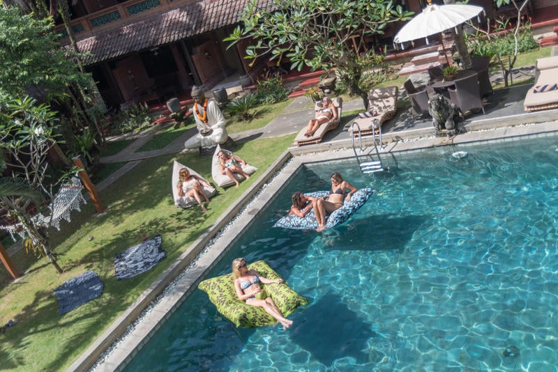 Puri Garden Hotel & Hostel best hostel in Bali with people laying on beanbags in and out of the outdoor pool in the sunshine
