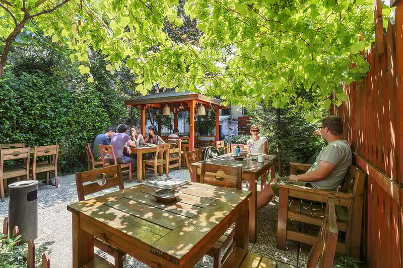 Lushy green tree covered outdoor dining area at Hush Hostel Lounge best hostels in Istanbul with guests sitting for free breakfast