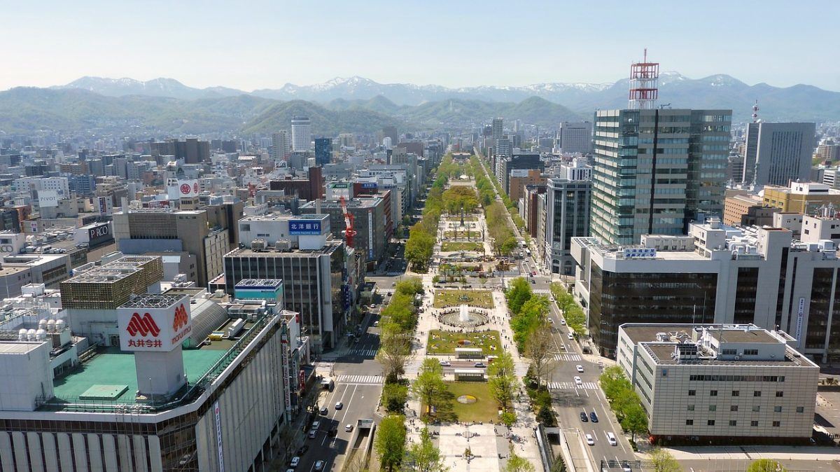 aerial vista of Sapporo, Japan, showcasing the city's streets and buildings with mountains in the background