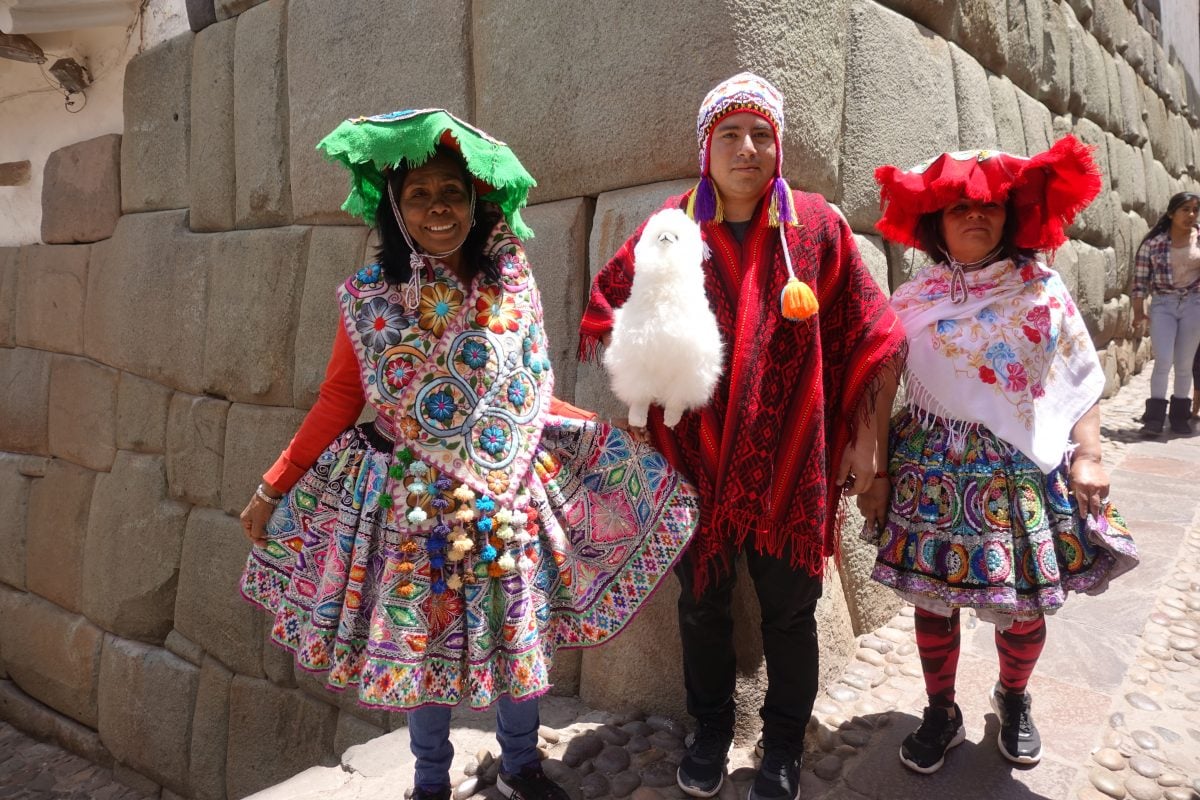 Local women in colourful and detailed traditional dress in Cusco, Peru with an alpaca.