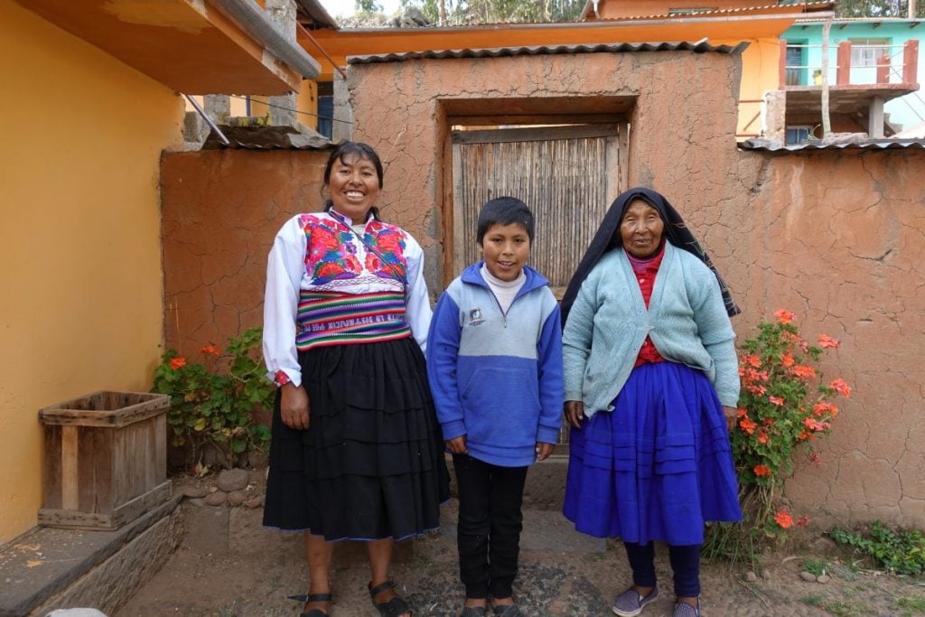 three members of a peruvian family smiling for a photo at thei homestay