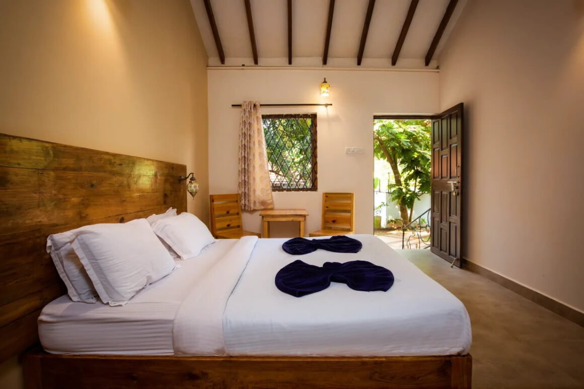 The Funky Monkey double room with a clean white bed and a door to the outside. A naturally lit private room