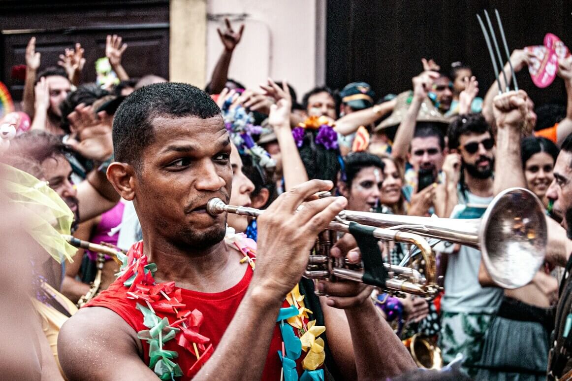Man playing trumpet in the middle of a dancing crowd at a carnival festival