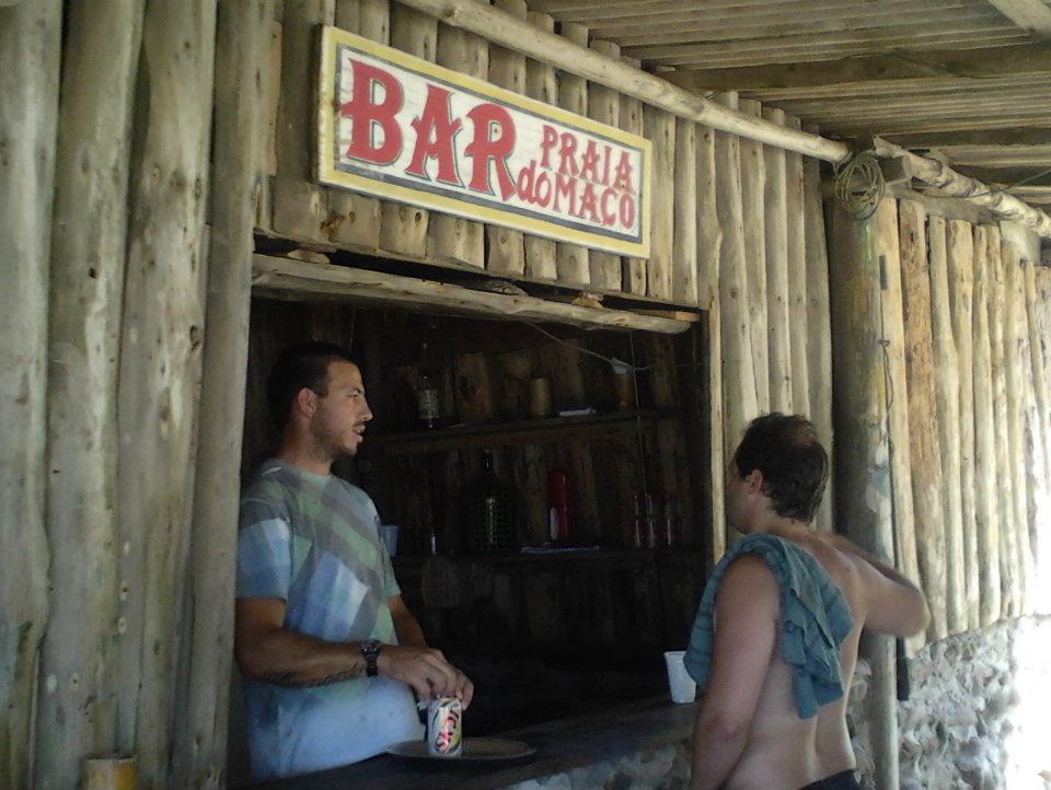 Two men stood below a bar sign on a wooden cabin.