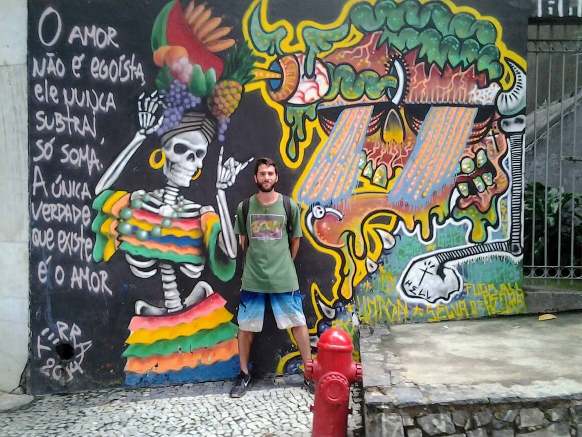 man standing in front of graffiti sign in brazil
