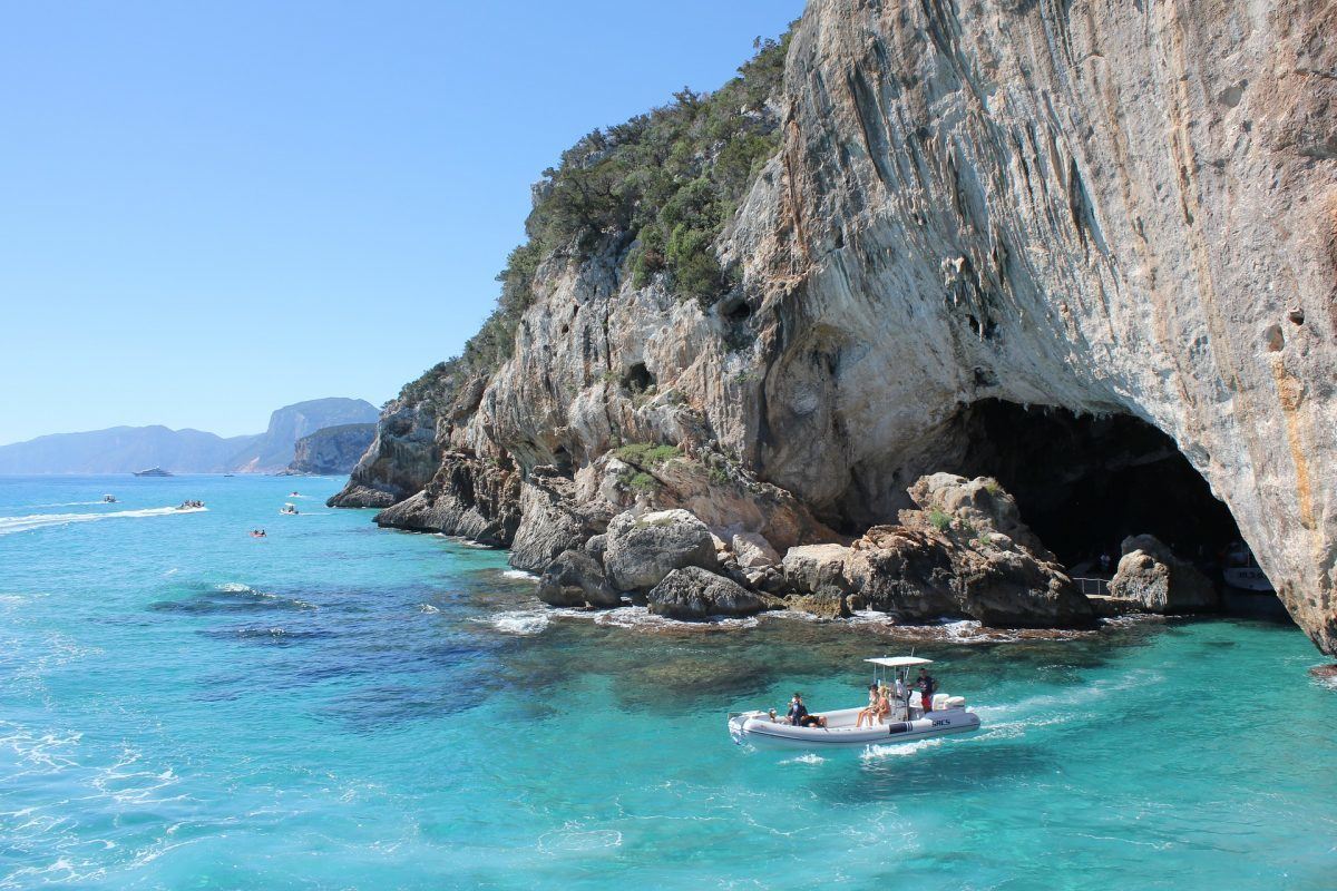 boat leaving sea cave in sardinia