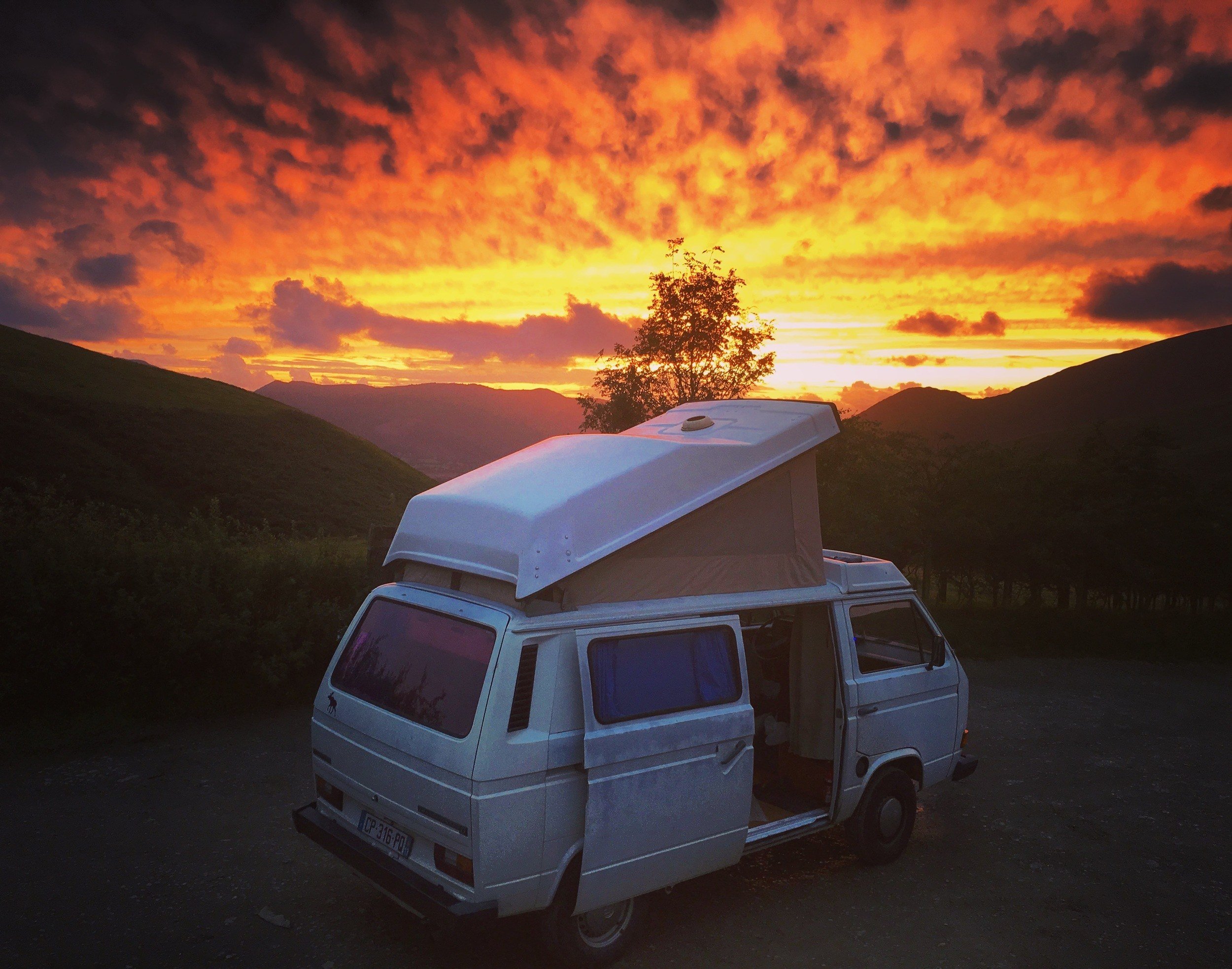 A van camping setup under a sunset