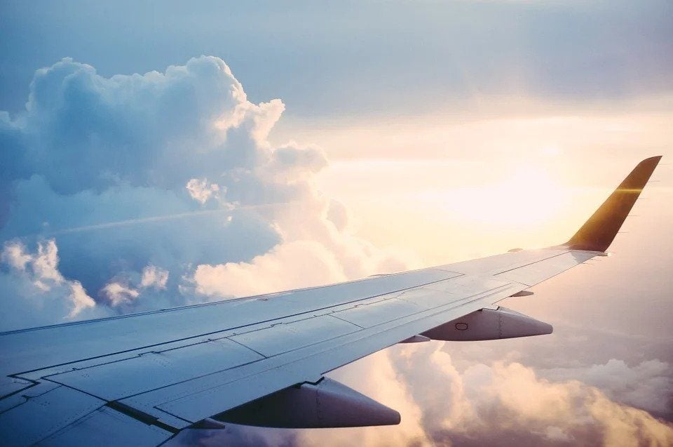 airplane wing with cloud and sun shining