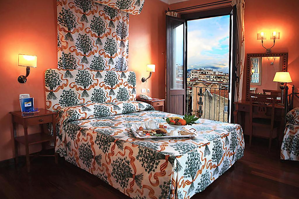 Hotel Vecchio Borgo best hostels in Palermo with a welcome platter on the bed and the doors open to a private balcony.
