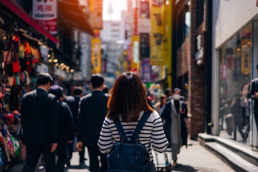 Woman wearing blue backpack walking through Hongdae Neighborhood