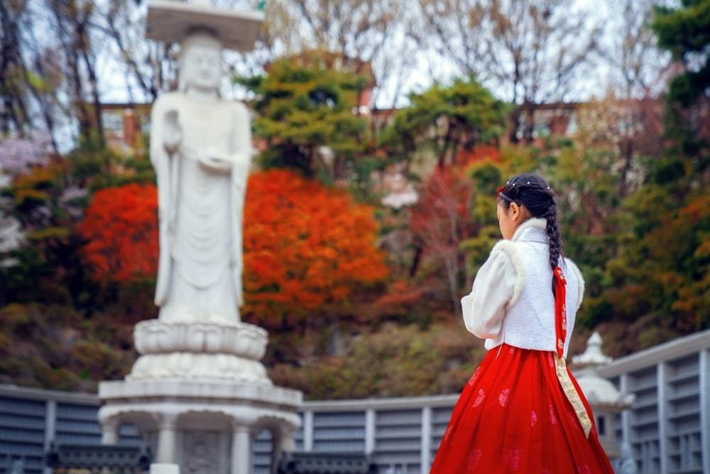 Woman in red dress standing next to statue in Gangnam