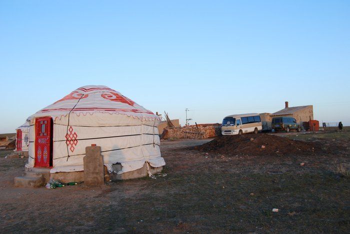 a white and red yurt sotuated among a small settlement in rural mongolia