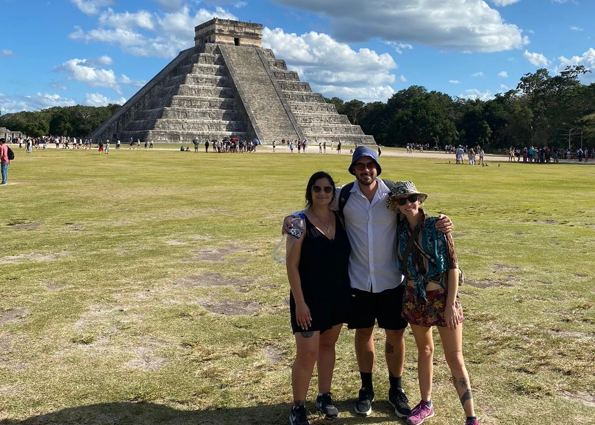 three people stood in front of Chichen Itza smiling on a sunny day