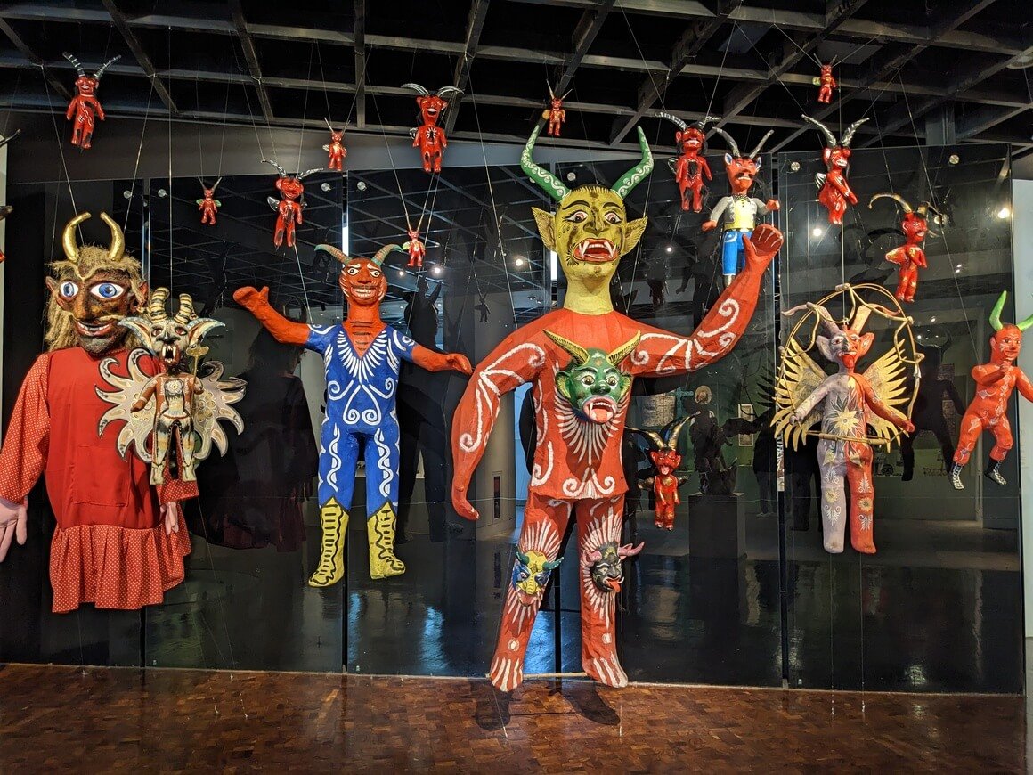 paper mache colourful Mexican diablos hanging in a museum 