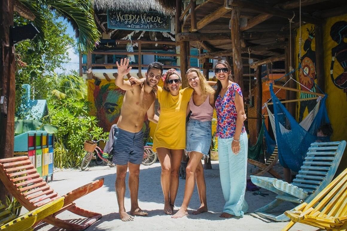 Group of guests smiling in a colourful hostel in Holbox, Mexico.