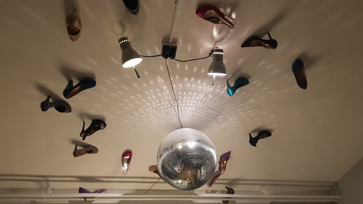 Shoes stuck on the ceiling around a glitter ball.