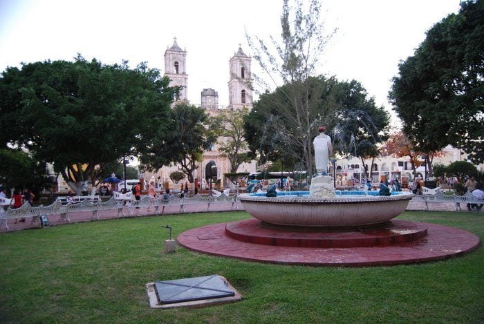 A fountain nestled amidst a park in Valladolid, with a church in the background