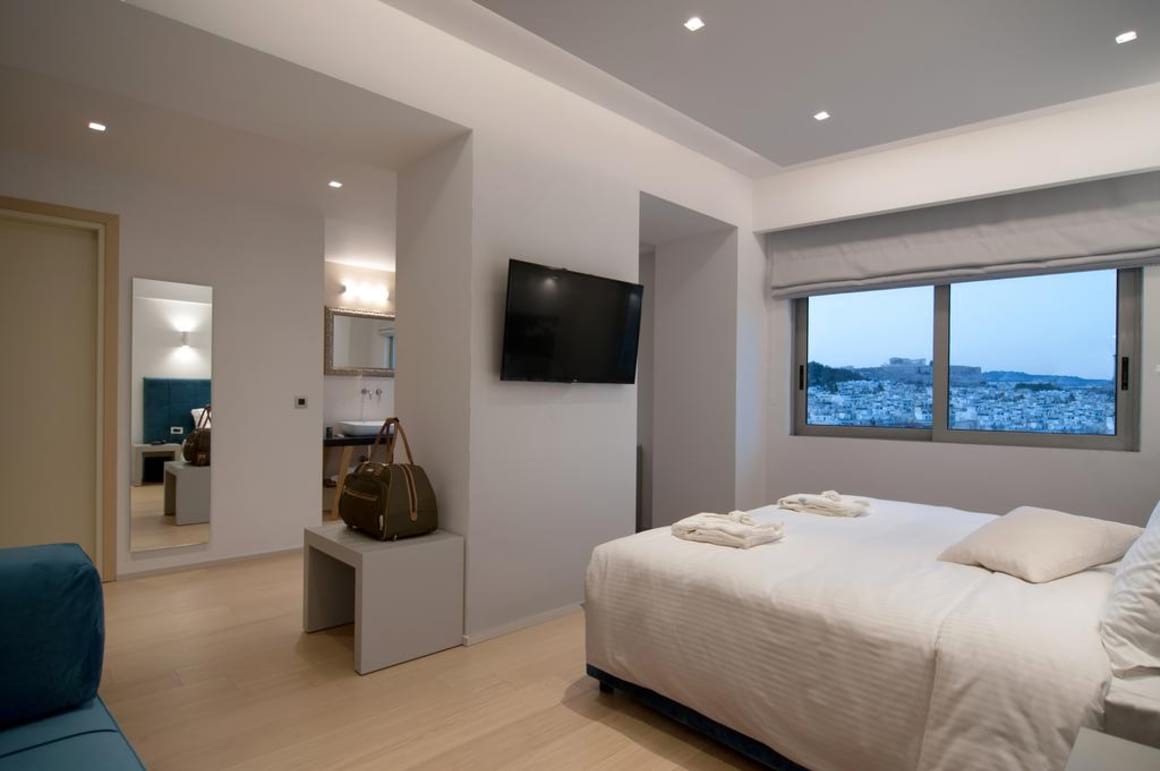 Bedroom in hotel with a TV, comfy bed and window with view over the city