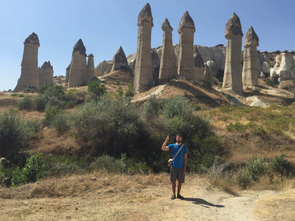 man posing with fairy chimneys in the background in the Valley of Love Cappadocia