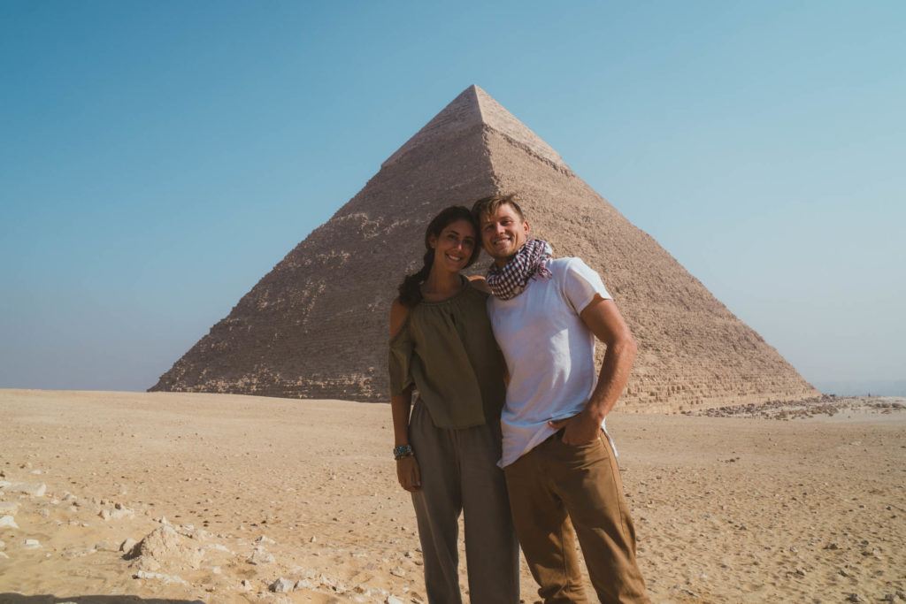 a couple posing with the Pyramids of Giza in the backdrop