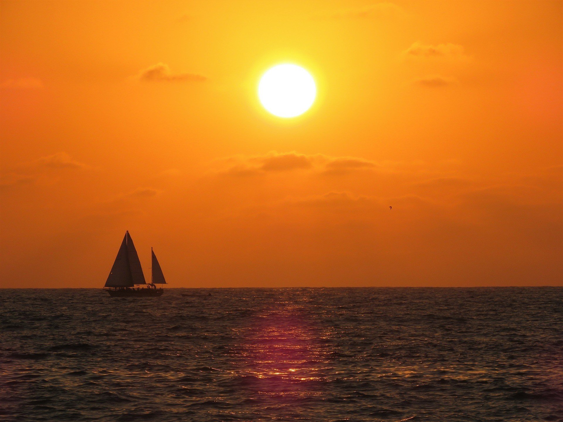 Beautiful sunset over the ocean with sail boats in the distance.