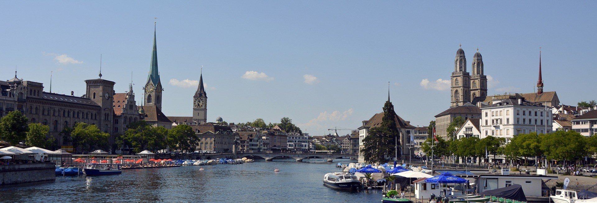 Best Hostels in Zurich view of the city across Lake Zurich with boats in the foreground and historic buildings in the background