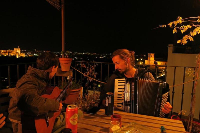 Cuevas Coloras best hostels in Granada Spain two friends playing instruments on a rooftop terrace