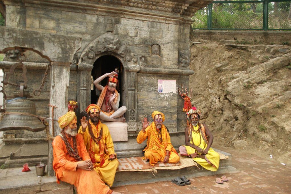 men in coloured robes and painted faces pay their respects at a temple in kathmandu