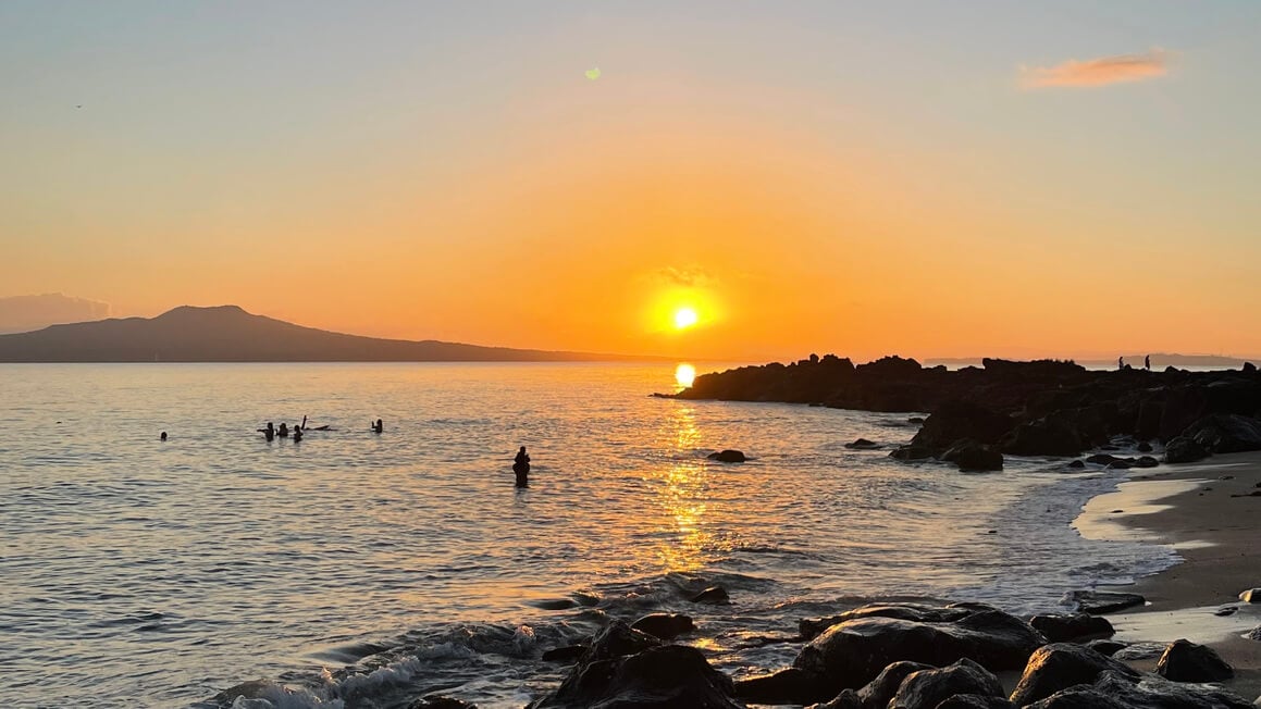 thorne bay in auckland, new zealand at sunrise looking over to rangitoto island