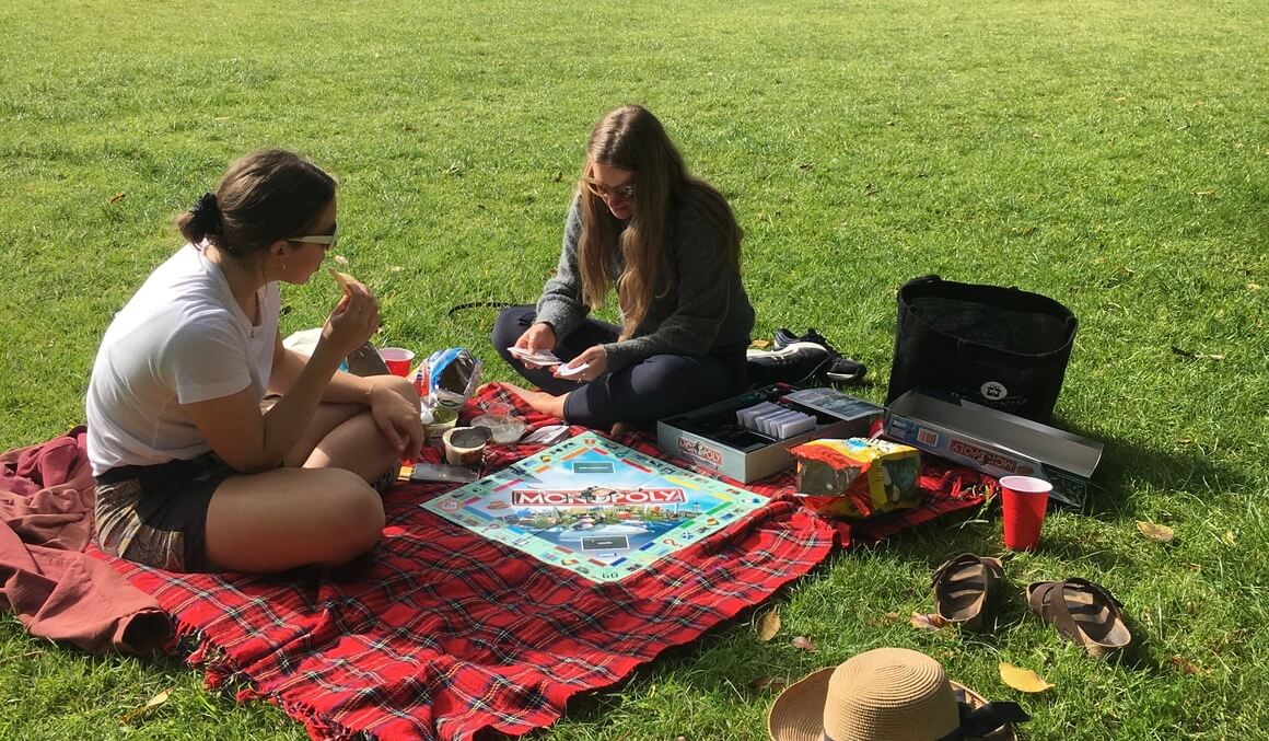 friends playing monopoly in the park