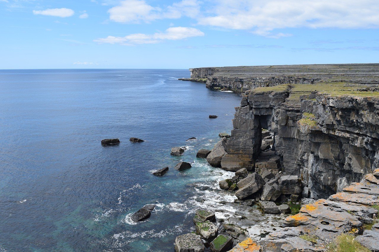 Rocky cliffs over the ocean. View from the top of the cliff. Stunning clear blue ocean and sky.