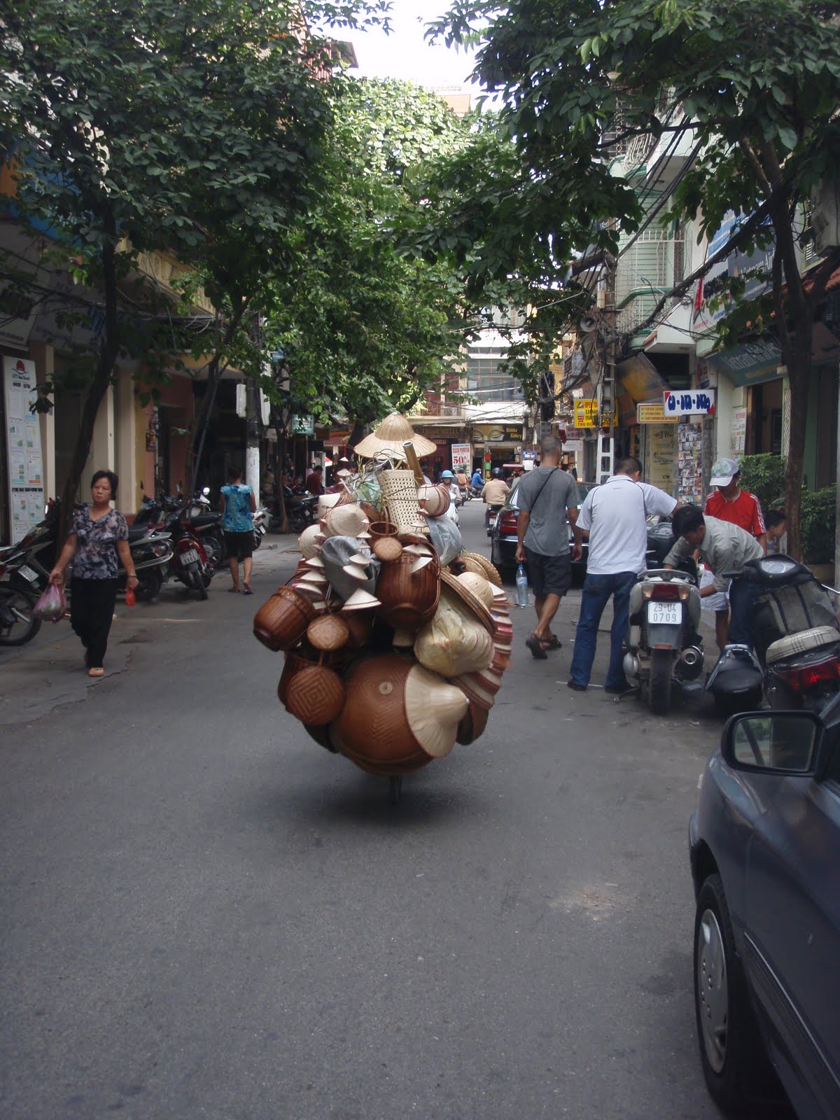 Basket merchant on a scooter in Old Quarter, Hanoi. The scooter has baskets hanging all over.